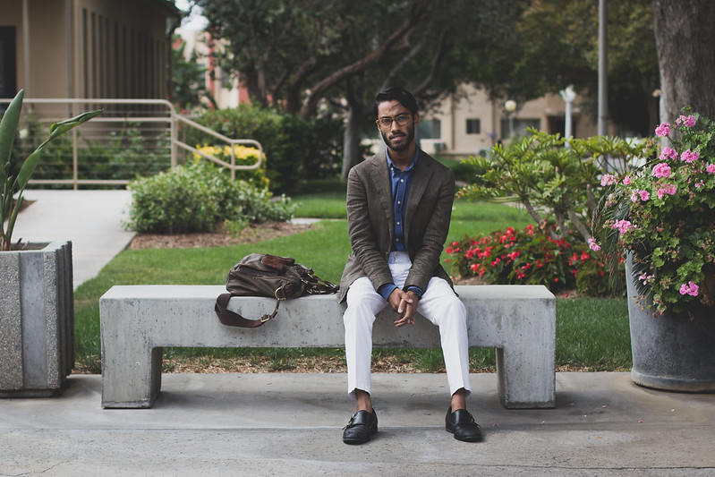 Rajesh wearing blues shirt, brown coat and gray pants