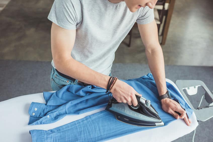 Man ironing blue shirt at home