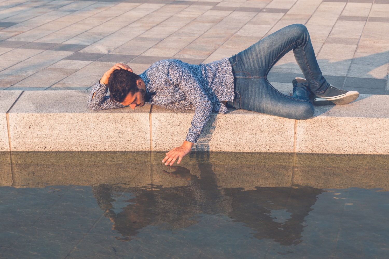 Young man looking at himself in the water