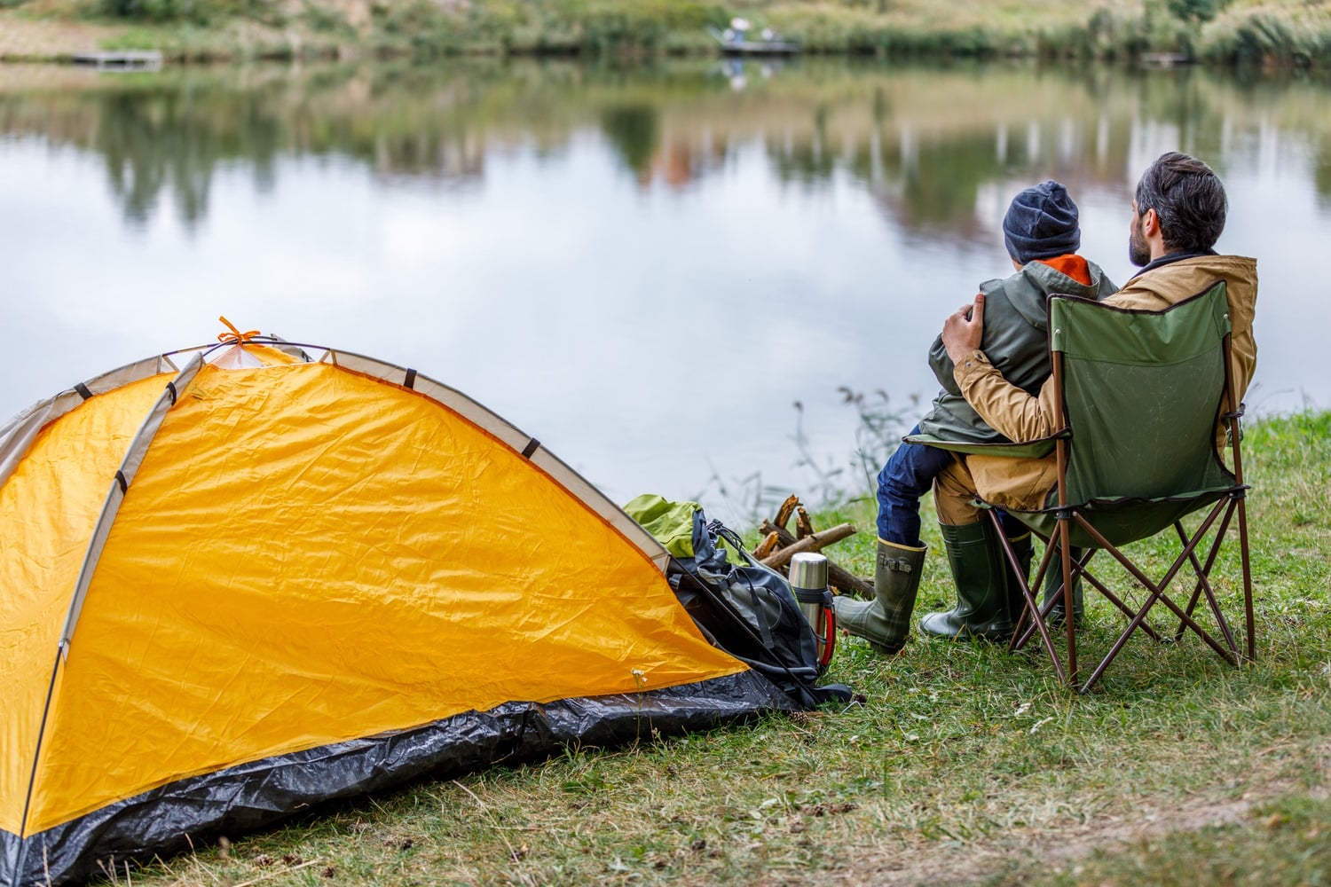 Father and son sitting along a tent