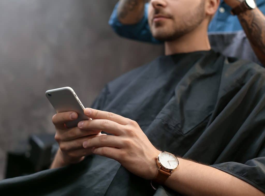 Professional hairdresser working with client in barbershop